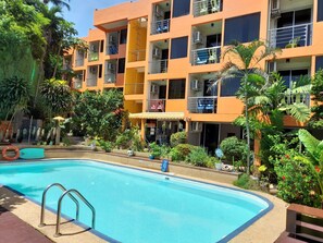A multi-story building with balconies, a swimming pool, and surrounding greenery. - Porterhouse Beach Hotel (Patong)