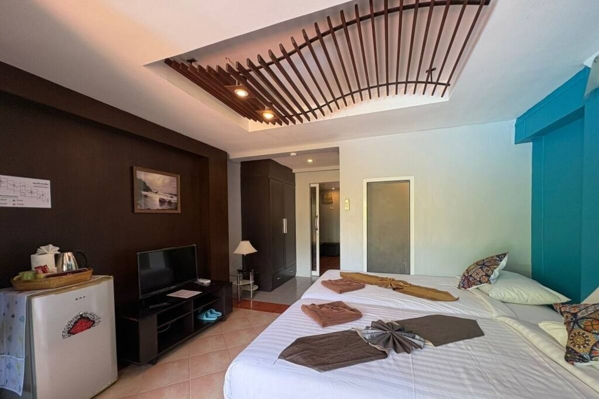 A hotel room with a bed, a television, a refrigerator, and a desk.