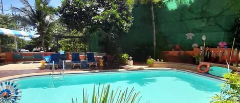 A swimming pool surrounded by lounge chairs and potted plants.