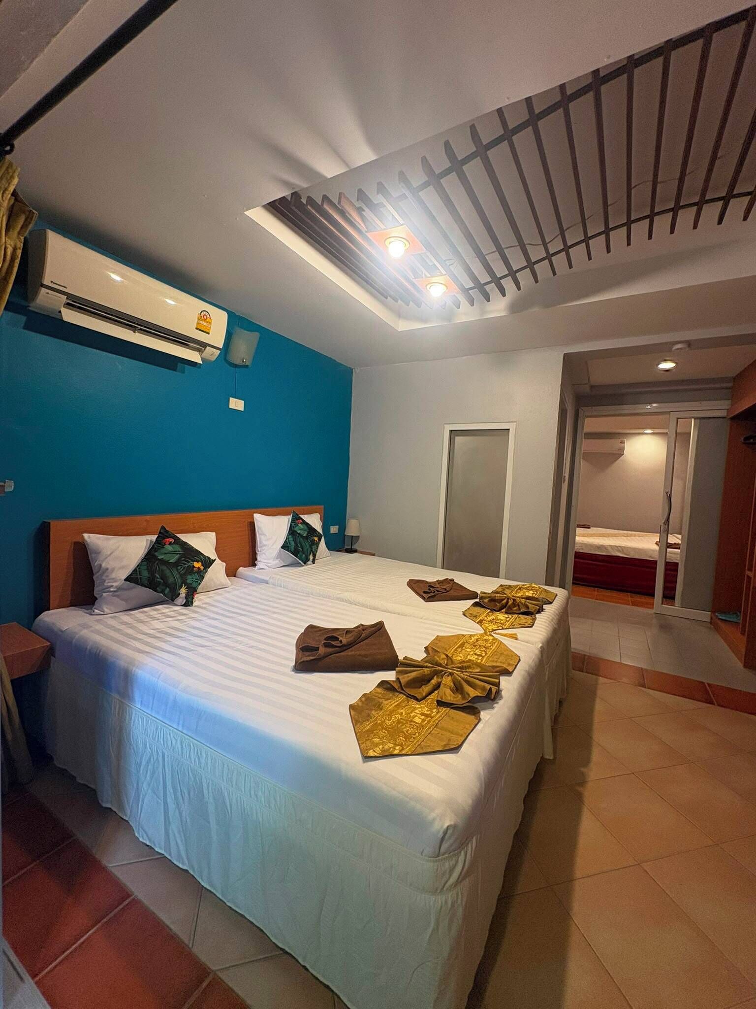 Une chambre d’hôtel avec un grand lit, un climatiseur, un ventilateur de plafond et une vue sur une autre chambre.