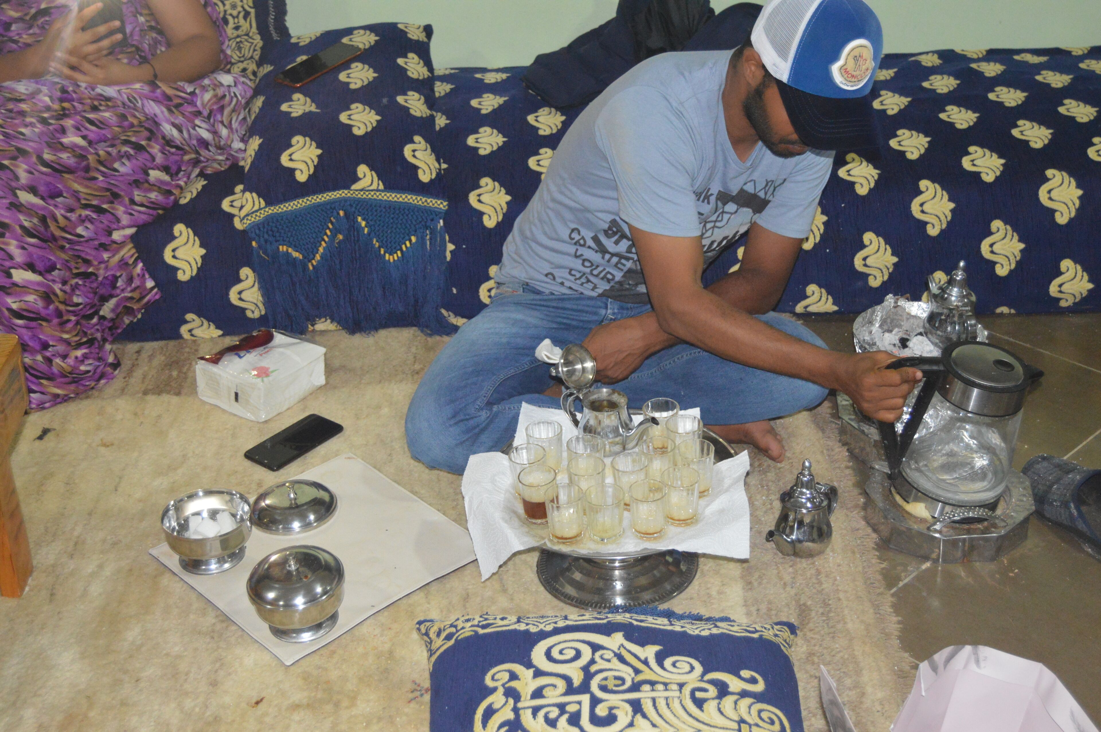 A room with a patterned sofa, a metal tray with glasses, and a coffee pot.