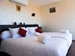 Ett hotellrum med en stor säng, två kuddar, en sänggavel och en väggmonterad luftkonditioneringsanläggning.