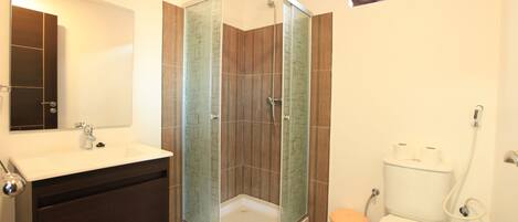 Un bagno moderno con doccia vetrata, lavandino bianco e water.
