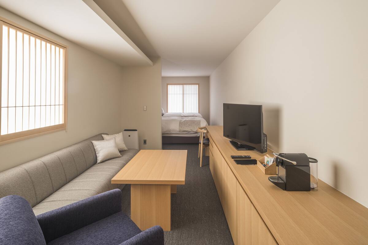 Une chambre d’hôtel compacte comprenant un canapé, une petite table, un téléviseur et une machine à café.