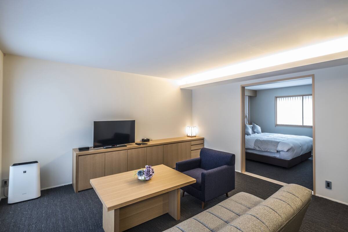 Une chambre d’hôtel moderne avec un bureau en bois, un téléviseur à écran plat, un canapé et un lit.