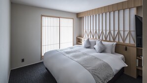 Een moderne hotelkamer met een groot bed, een televisie en een houten hoofdeinde.