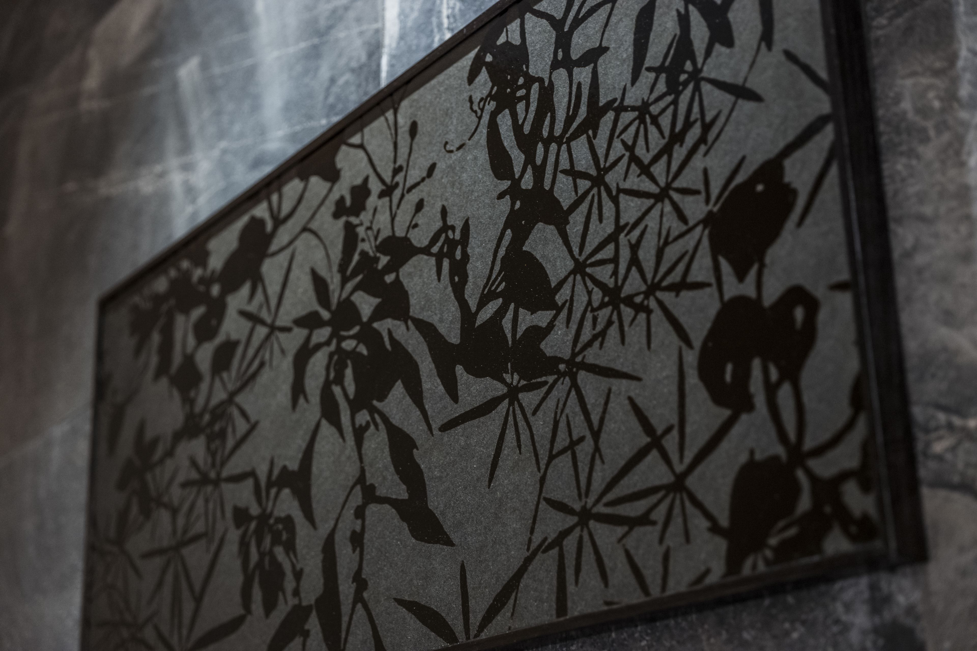 A wall with a decorative panel featuring a floral and geometric pattern.