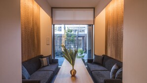 Een moderne kamer met een zithoek, een houten tafel en een uitzicht door een groot raam.