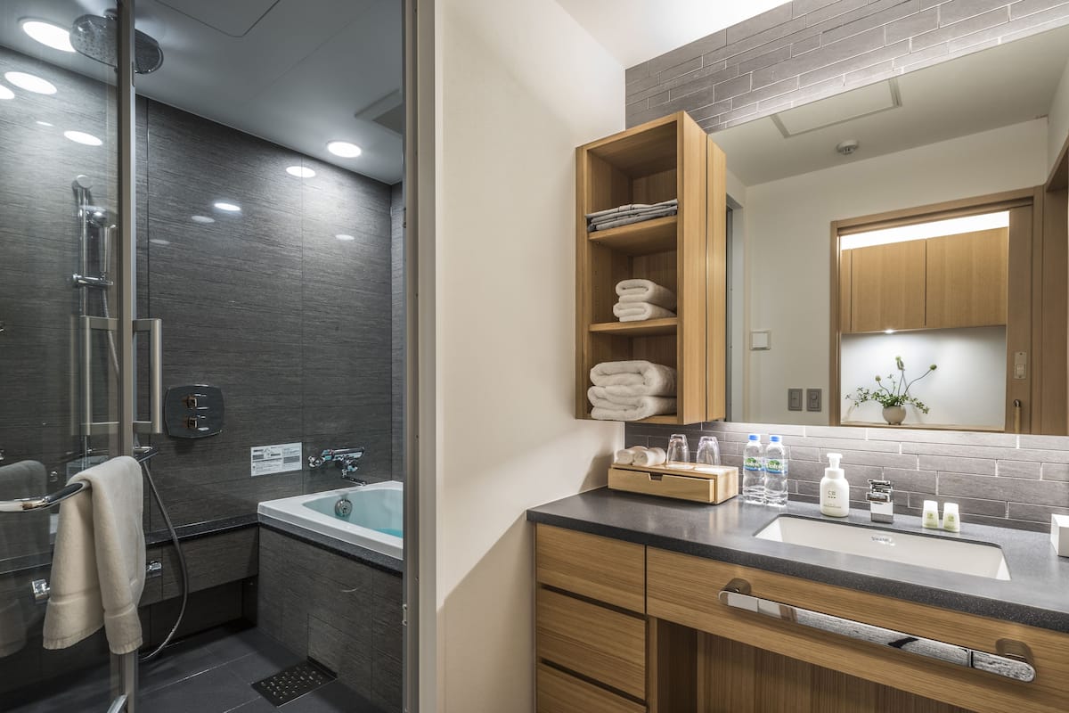 deluxe twin room with living area | bathroom | combined shower/bathtub, deep-soaking bathtub, rainfall showerhead