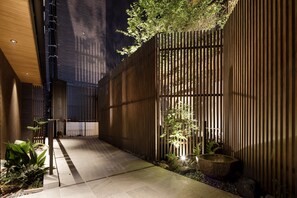 A modern outdoor area with a wooden fence, a stone basin, and a pathway. - Tomoya Residence Hotel Kyoto Nijo Takakura (Kyoto)