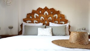 A neatly made bed with a wooden headboard, striped pillows, and a woven hat on the bed. - Soraya Yoga Wellness Center (Gili Trawangan)