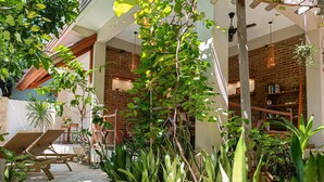 A sunlit patio with lounge chairs, a brick wall, and a bookshelf. - Soraya Yoga Wellness Center (Gili Trawangan)