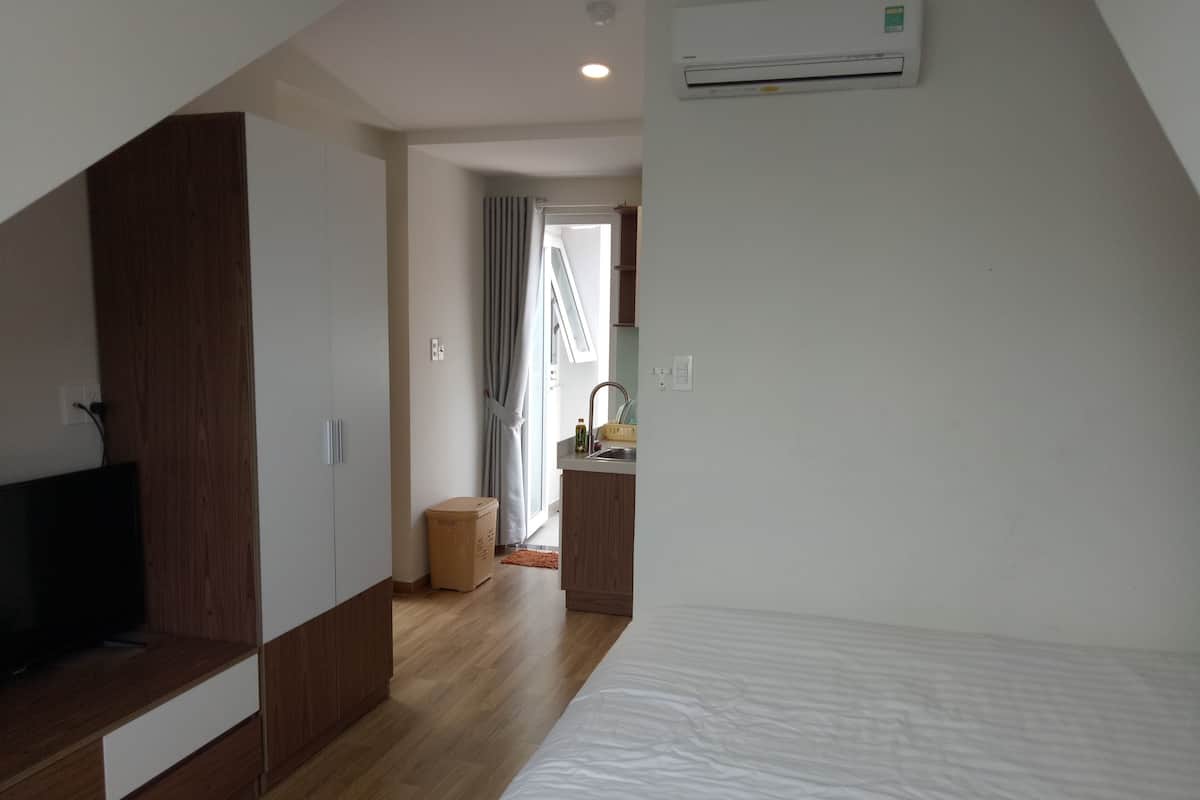 Een moderne slaapkamer met een houten garderobe, een bed en een kitchenette.