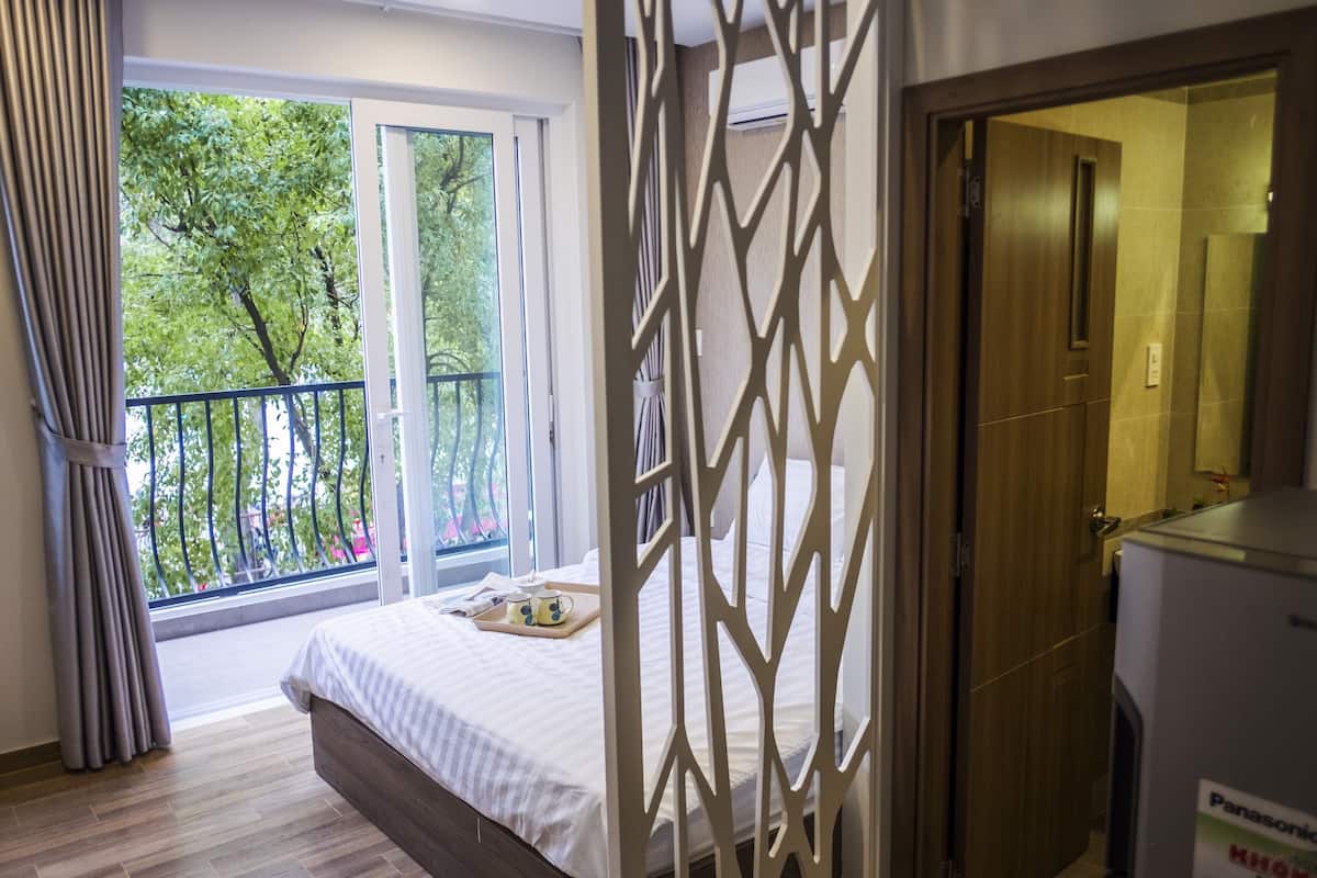 Een hotelkamer met een bed, een balkon, een houten deur en een Panasonic koelkast.