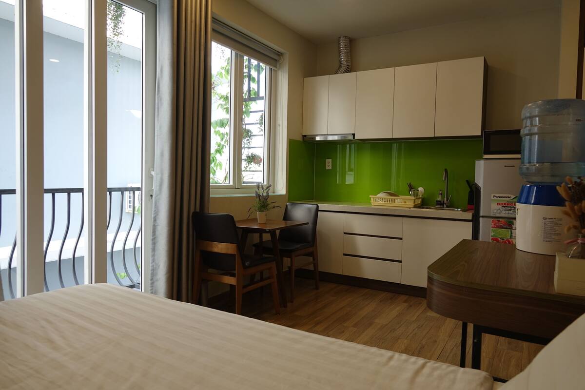 Hotelkamer met een bed, een eettafel met stoelen, een kitchenette met een magnetron en een grote waterdispenser.