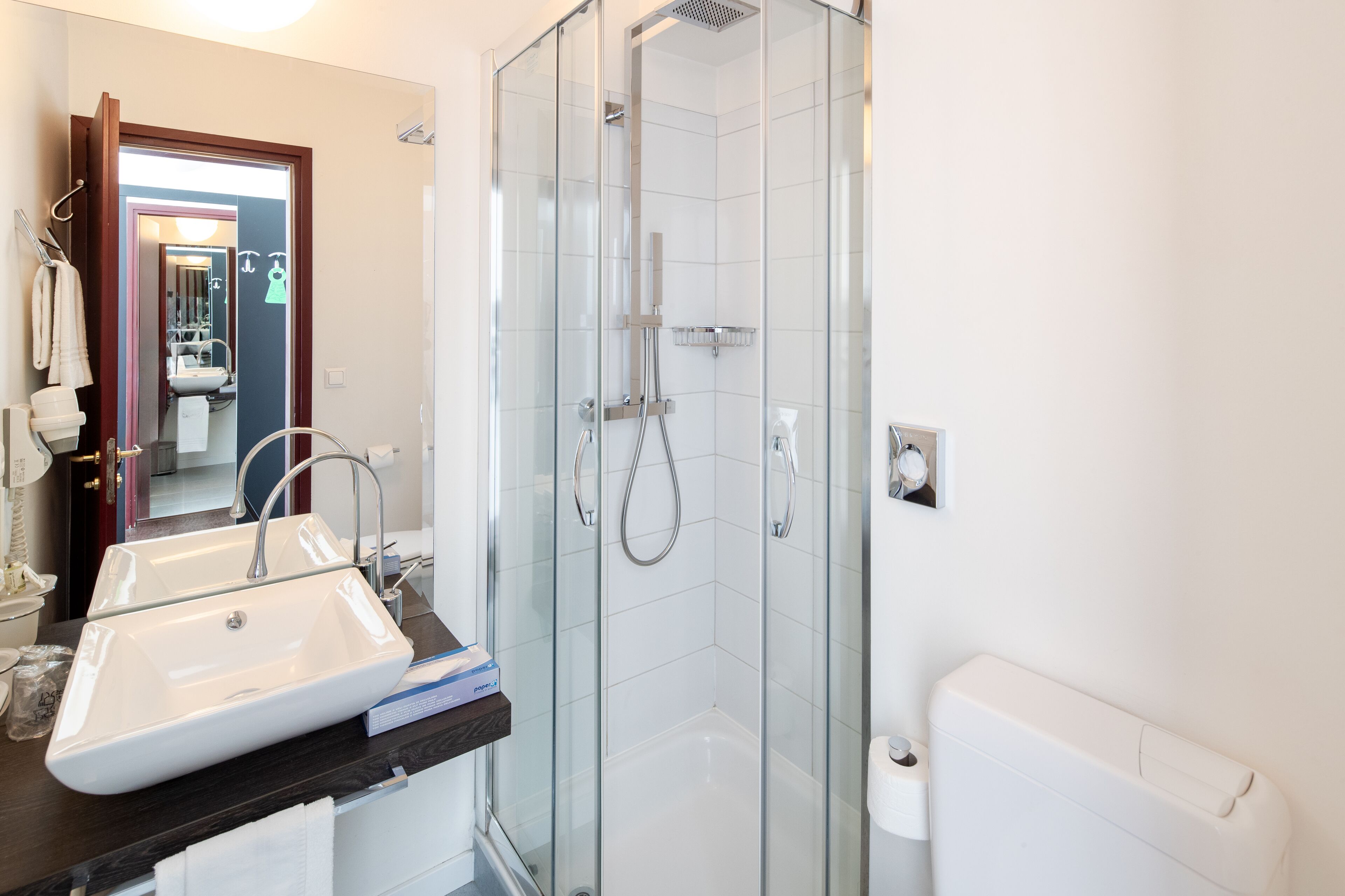 A modern bathroom with a glass-enclosed shower, a white sink, and a toilet.