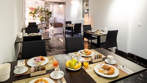 Una mesa en el comedor de un hotel con platos de comida, tazas y cubiertos.