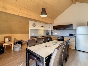 A modern kitchen with wooden cabinets, a stainless steel refrigerator, and a dining area with a wooden table and chairs. - 2-star apartment for 10 pers, 3 br, near ski lift, parking (La Toussuire)