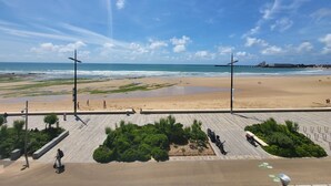 A beach with a paved walkway, greenery, and a view of the ocean. - Oceanfront 2-Room Apt with Direct Beach Access in Les Sables-d'Olonne (Les Sables-d'Olonne)