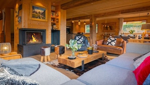 A cozy cabin interior with a fireplace, wooden walls, a dining area, and a living room with a sofa and coffee table. - Chalet Bonnevie - family home for 10, spa & mountain views - OVO Network (Les Villards-sur-Thônes)