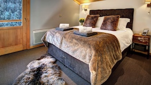 A bedroom with a large bed, a wooden door, a radiator, and a fur rug.
