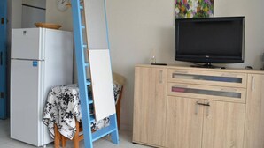 Ein kompakter Wohnbereich mit einer Küchenzeile, einem Fernseher und einem Bild an der Wand.