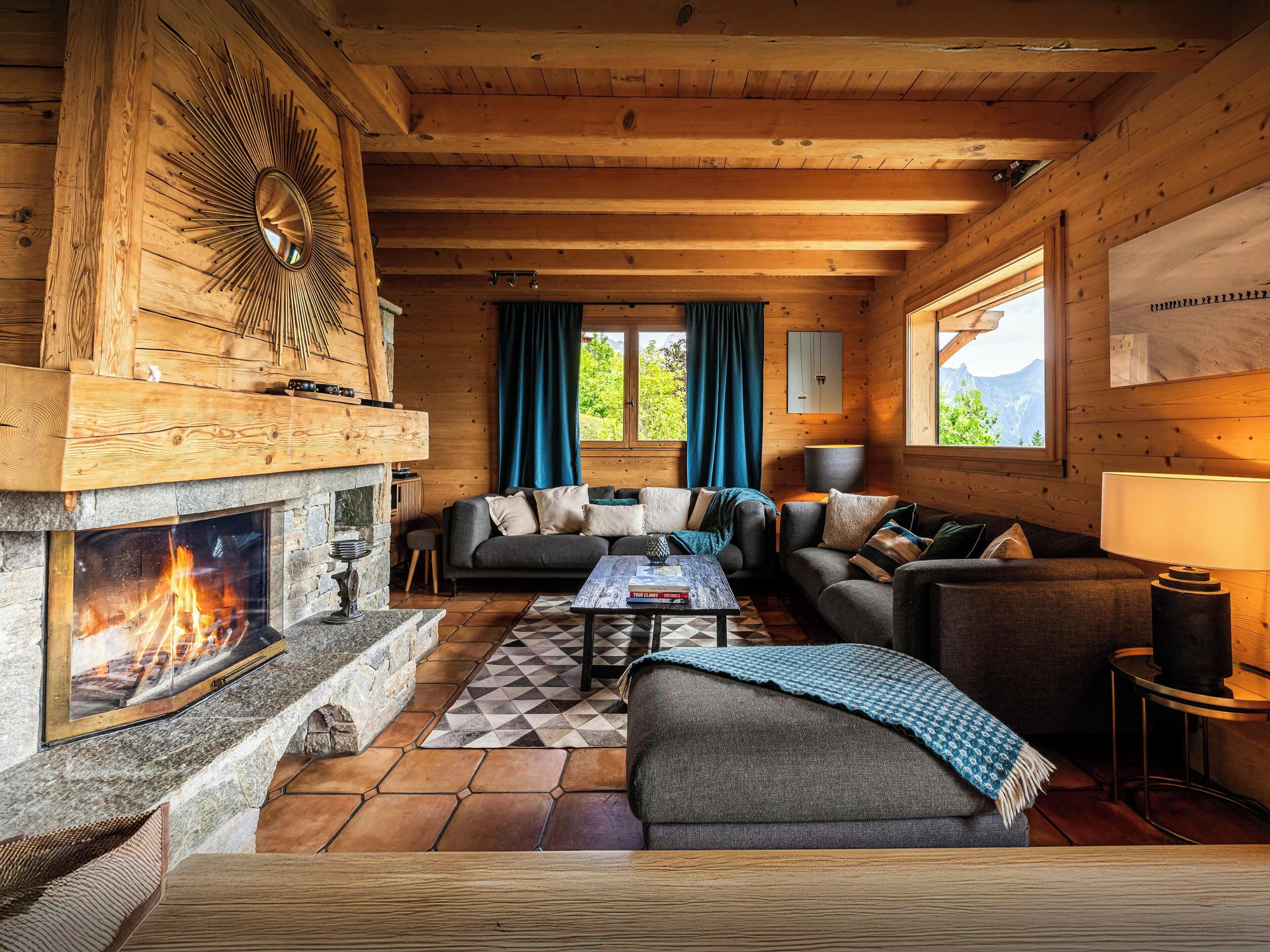 L’intérieur d’un chalet accueillant, avec une cheminée, des murs en bois, un canapé et une table à manger.