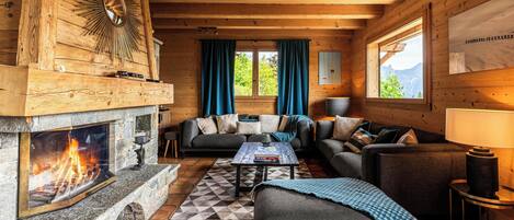 L’intérieur d’un chalet accueillant, avec une cheminée, des murs en bois, un canapé et une table à manger.