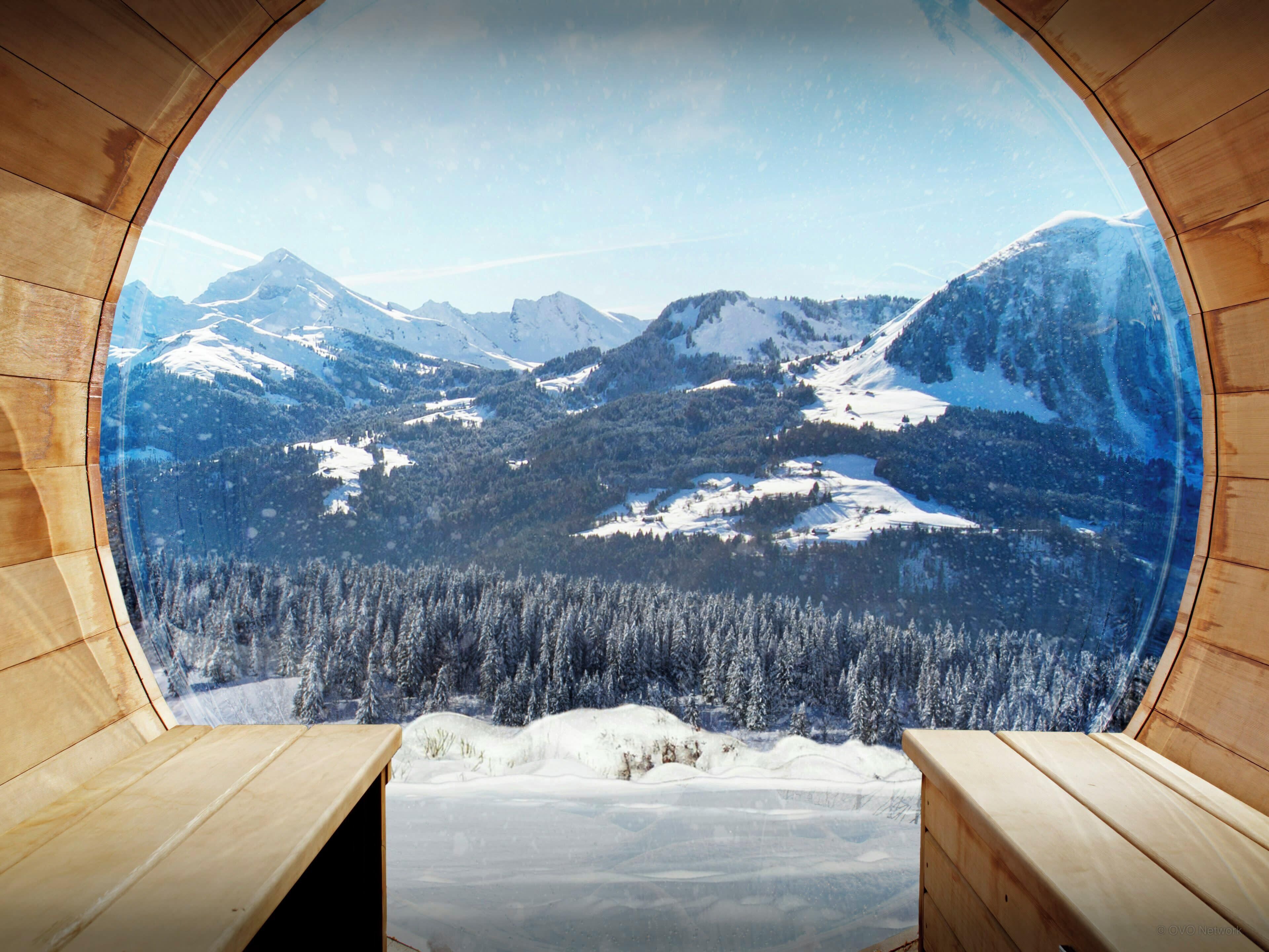 Une vue panoramique à travers une fenêtre à cadre en bois, offrant un paysage de montagnes enneigées, de forêts denses et d’un ciel dégagé.