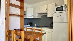 Une cuisine avec des meubles blancs, une table à manger en bois et un four à micro-ondes.