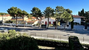 Une rue résidentielle bordée de maisons, d’arbres et de voitures garées.