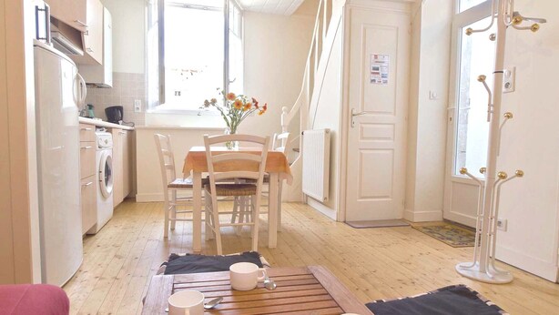 A compact kitchen with a dining area, a radiator, and a coat rack.