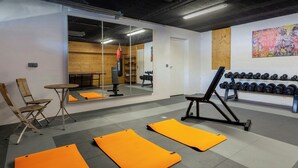 A gym with exercise mats, a punching bag, and a wall-mounted dumbbell rack. - Chalet Le Mousqueton - ski base for 14 spa & mountain views - OVO Network (La Clusaz)