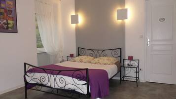 Un dormitorio con cama, mesitas de noche, una ventana con cortinas y una puerta.