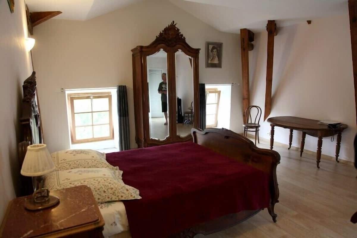 Ein Schlafzimmer mit einem großen Bett, einem Holzschrank, einem Spiegel, einem Tisch und einem Stuhl.