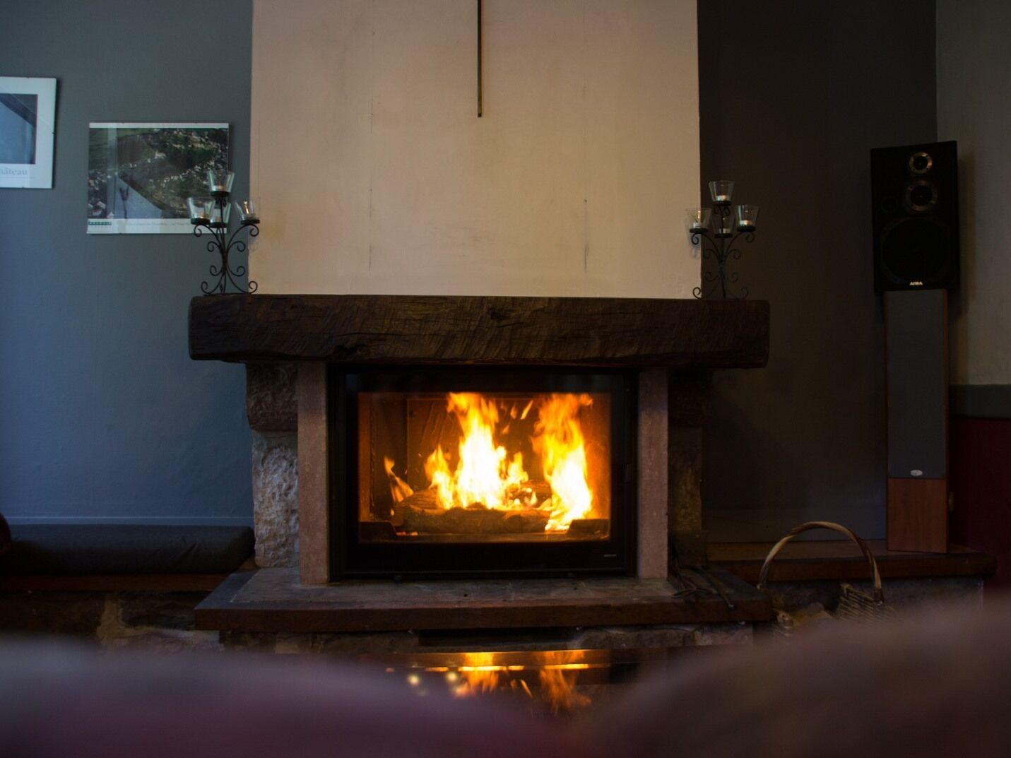 Une cheminée avec un feu qui crépite à l’intérieur, une étagère au-dessus et un haut-parleur sur le côté droit.