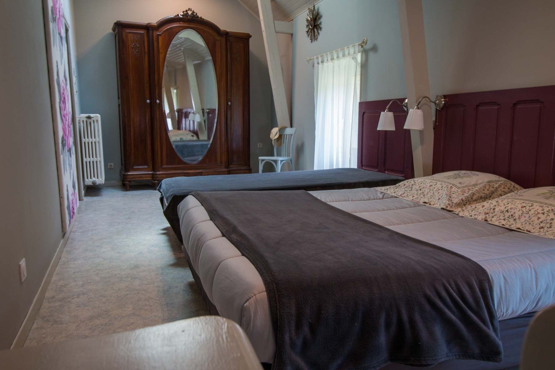 Un dormitorio con dos camas, un aparador, un espejo y un radiador.