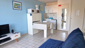 A compact living space with a kitchenette, a dining area, a television, and a sofa.