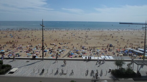 Een strand met veel parasols en mensen.