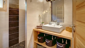 Ein modernes Badezimmer mit großem Waschbecken, Spiegel und Ablageflächen.
