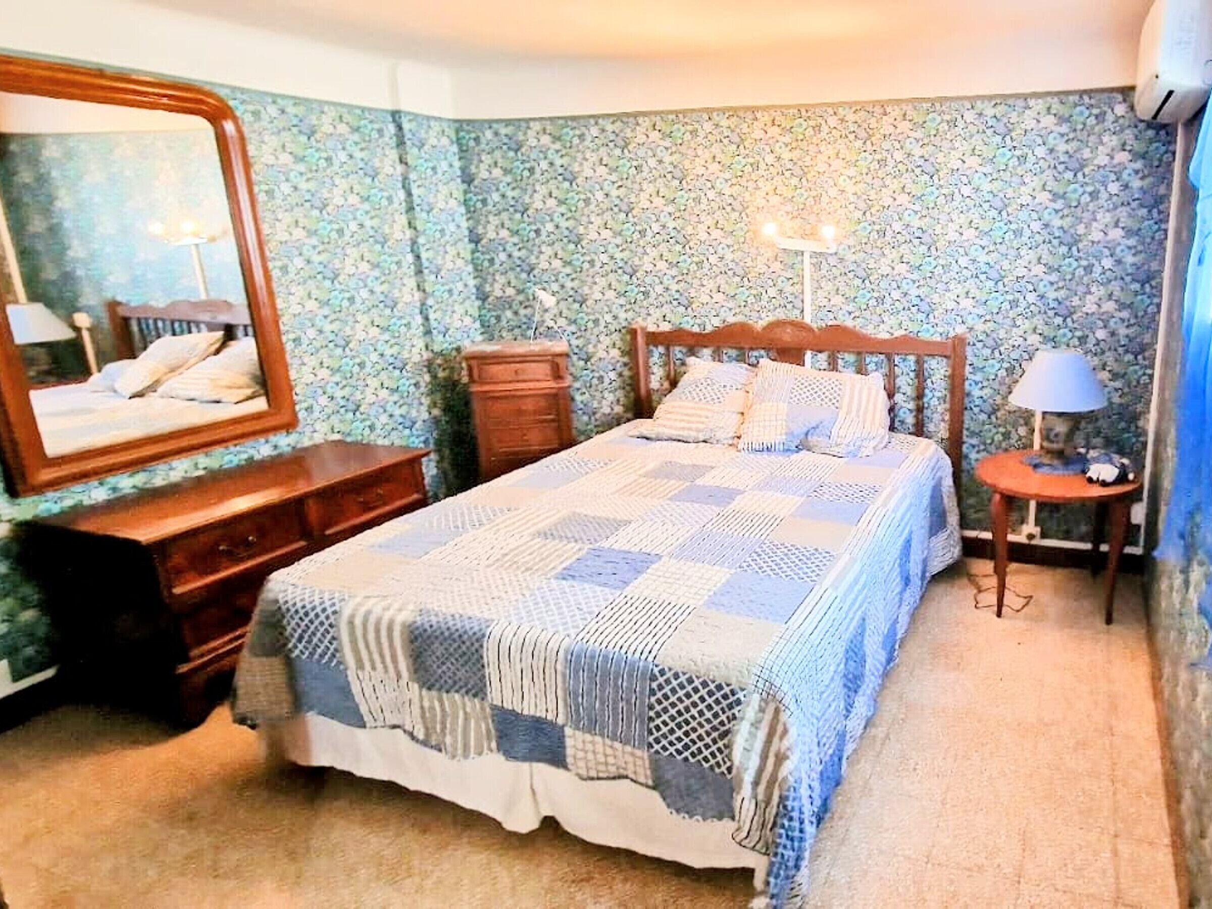 Un dormitorio con cama, cómoda, espejo y mesita de noche.