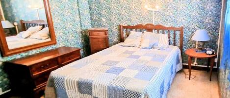 Un dormitorio con cama, cómoda, espejo y mesita de noche.