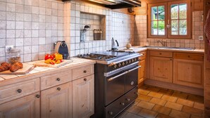 Una cocina con estufa, armarios de madera, una ventana y salpicadero de azulejos.