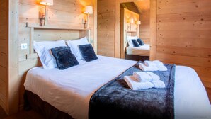 Un dormitorio de cabaña de madera con una cama, dos lámparas fijadas a la pared y un espejo.