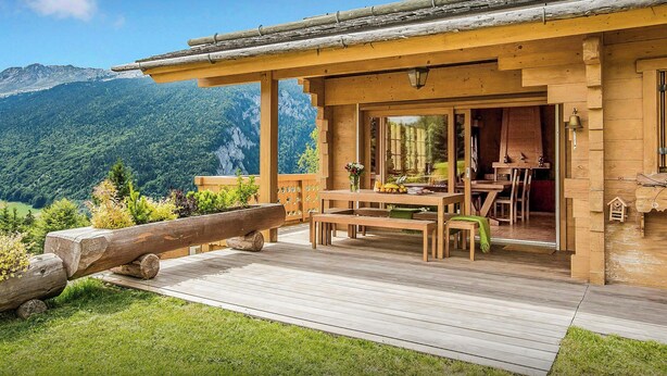 Una cabaña de madera con un balcón, un comedor y vistas a la montaña.