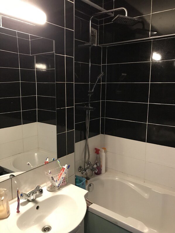 A bathroom with black tiled walls, a white sink, and a bathtub. - Time Away From Home (Asse)