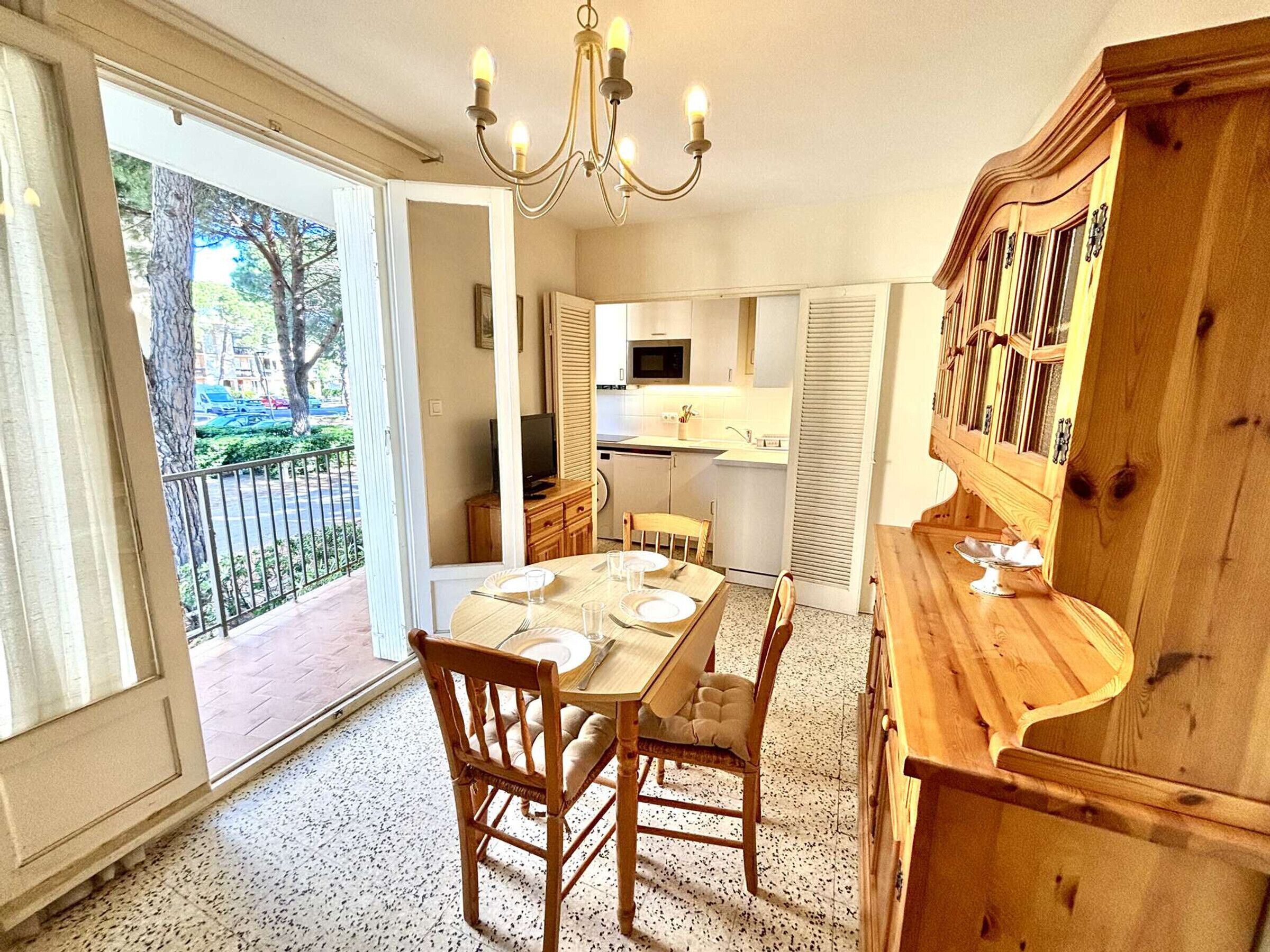 A dining area with a table set for four, a wooden cabinet, and a television in the background.