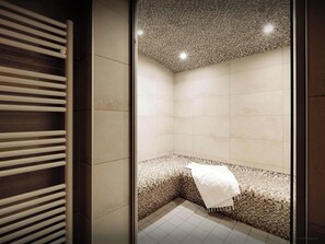 Une salle de bain moderne avec un sol carrelé, un banc sur lequel est posée une serviette blanche, et un plafond orné d’un motif en mosaïque.