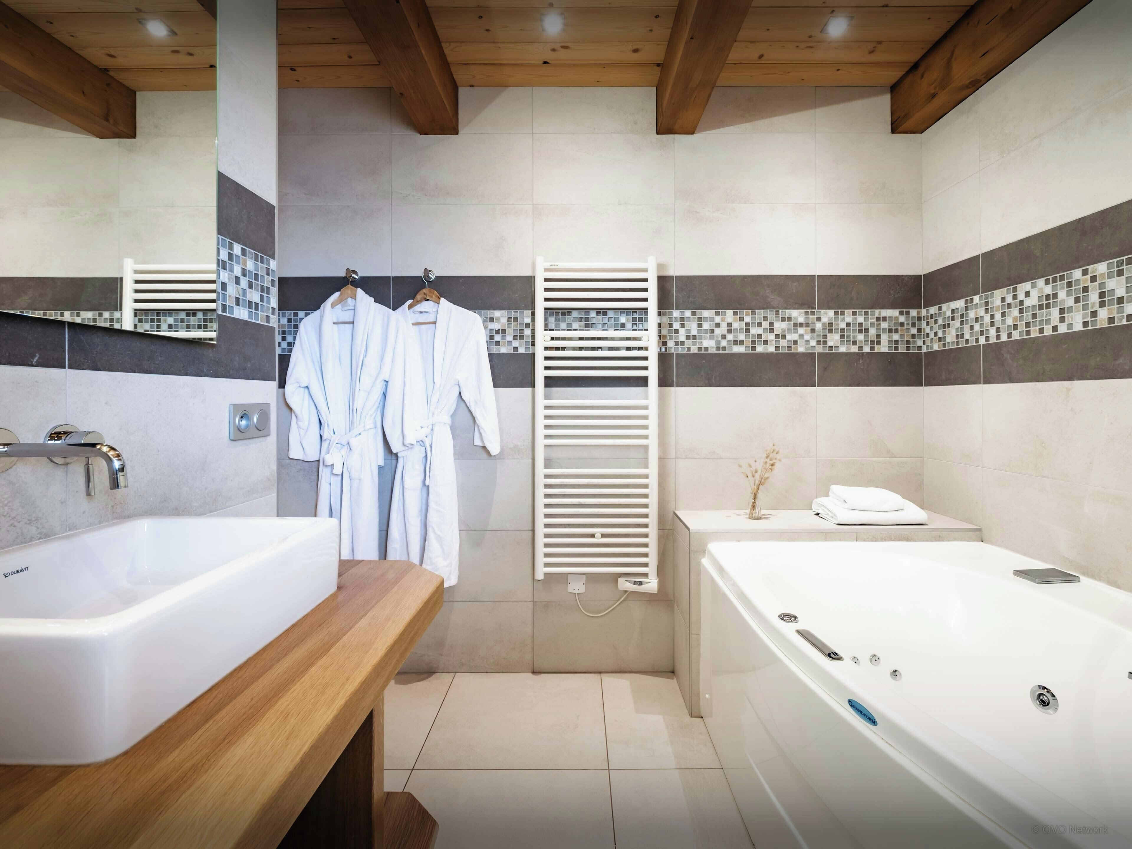 Een moderne badkamer met een bad, een douchegedeelte en een wastafel met spiegel.