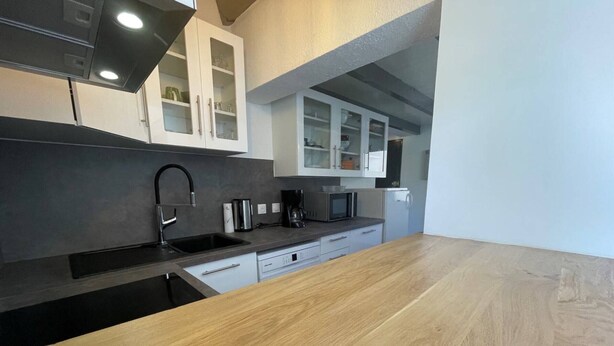 A modern kitchen with a wooden countertop, stainless steel appliances, and white cabinetry.